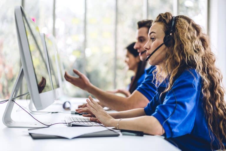 Call center customer service agents working with headsets on computers.