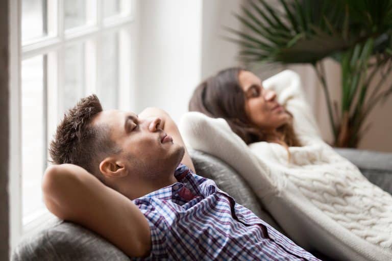 Relaxed couple resting on sofa, enjoying a peaceful moment.