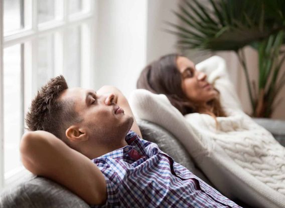 Relaxed couple resting on sofa, enjoying a peaceful moment.
